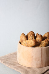 small French baguettes in a wooden bowl on canvas napkin against light background