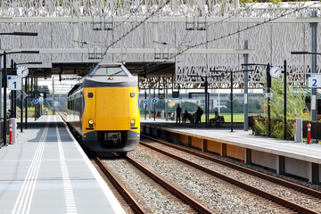 ICM Intercity train called Koploper rushes along platform at station Lansingerland Zoetermeer