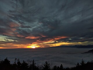 Fototapeta na wymiar Fog on the plain of Friuli and view of Piancavallo at sunset from Mount Bernadia in Tarcento