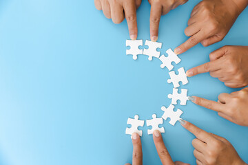 A group of businessmen assemble a jigsaw puzzle. Successful teamwork concept, help and support in...