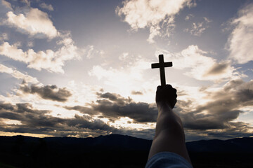 Silhouette of woman hands praying with cross  in nature sunrise background,  Crucifix, Symbol of...