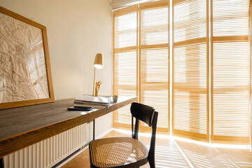 Cozy worplace with wooden table, chair and window blinds on background in bright living room at home