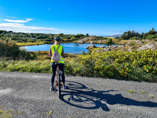 Lady with bicycle taking smartphone photos of a lake by Burtonport, County Donegal, Ireland - Seen...