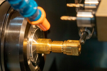 The multi-tasking CNC lathe machine swiss type milling the brass shaft parts.