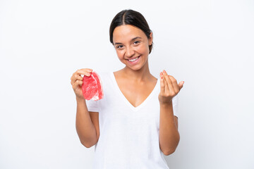 Young hispanic woman holding a piece of meat isolated on white background inviting to come with hand. Happy that you came