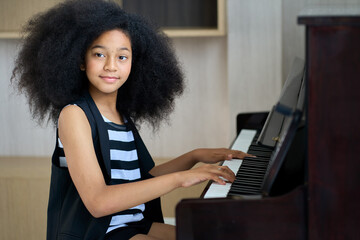 Smiling teenage girl looking at you for play piano in home living room