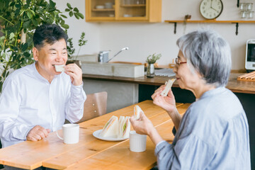 家で朝食をとるシニア・高齢者の夫婦
