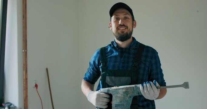 Satisfied worker performs home bathroom demolition, general apartment renovation with hammer, tile chipping, construction worker with experience.