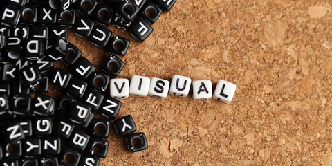 Closeup of word on plastic cube on wooden desk background concept - visual