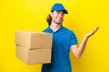 Obraz na płótnie Canvas Delivery handsome man isolated on yellow background extending hands to the side for inviting to come