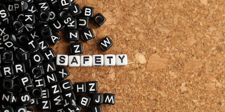 Closeup of word on plastic cube on wooden desk background concept - safety