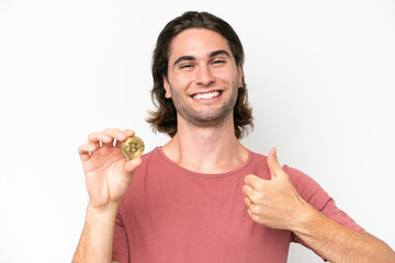 Young handsome man holding a Bitcoin isolated on white background with thumbs up because something good has happened