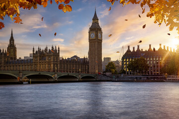 Beautiful autumn view of the Westminster Bridge and palace with Big Ben clocktower in London, golden branches and leaves and soft sunset light
