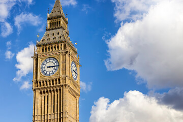 Close-up view of the Elizabeth Tower, or Big Ben, in front of blue sky and light clouds with...