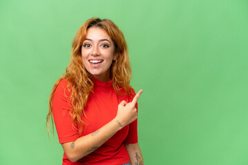 Young caucasian woman isolated on green screen chroma key background surprised and pointing side