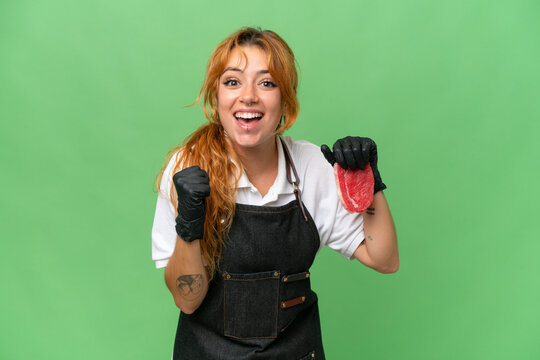 Butcher caucasian woman wearing an apron and serving fresh cut meat isolated on green screen chroma key background celebrating a victory in winner position