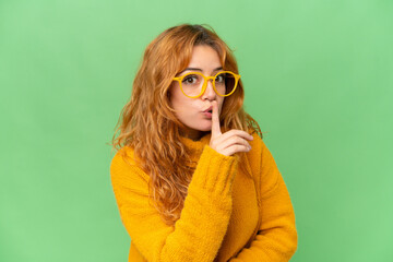 Young caucasian woman isolated on green screen chroma key background With glasses and doing silence gesture