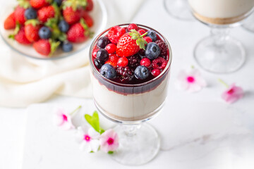Milky sweet, delicious pudding topped with forest fruits and fruit sauce.
