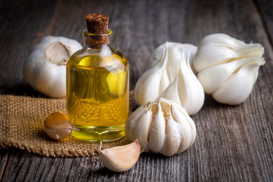 Fresh garlic and garlic oil on the wooden background