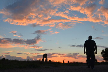 Uomo in controluce al tramonto con arco romano sullo sfondo