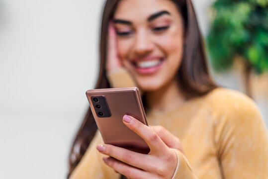Closeup shot of mobile phone, being used by happy young woman.
