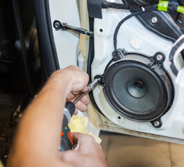 Fototapeta premium A car repairman repairs a car door. An auto mechanic works with the car door. A man works at a service station.