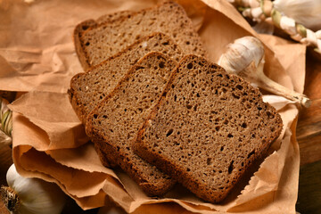 still life of food in a rural style on a dark wood background, rye bread and garlic, concept of fresh vegetables and healthy food