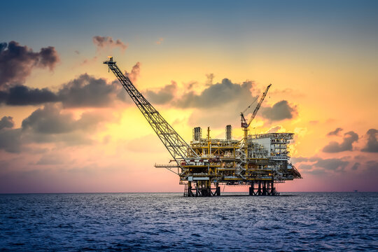 Offshore oil and rig platform in sunset or sunrise time. Construction of production process in the sea. Power energy of the world.