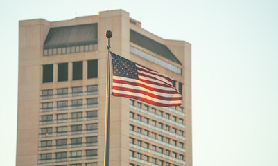 National flag of United States of America winding in sunset light against landmark buildings from...