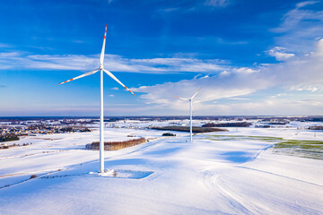 Wind turbine on snowy field in winter at sunrise.