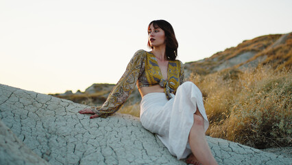 Beautiful Girl Observes the Sunset Sitting in the Mountains on the Rock