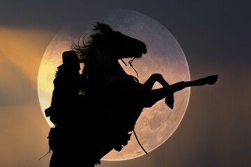 Silhouette of a cowboy riding a horse against the moon