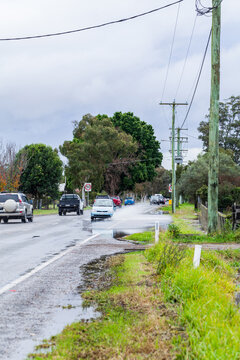 Flood water forming puddle on highway road through town with car driving through