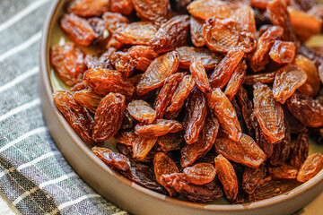 There are many naturally dried red raisins on the table - obrazy, fototapety, plakaty
