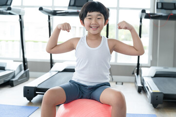 Fototapeta premium Asia kid boy exercise with exercise ball at fitness gym