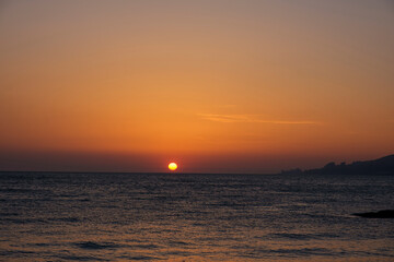 Fototapeta premium Gorgeous sea sunset landscape. MIrror reflection of dawn on sea surface. Red sun on cloudless sky, apocalypse. Blurred, out of focus