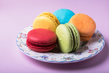 Macaroon cakes on a dessert saucer on a pink background