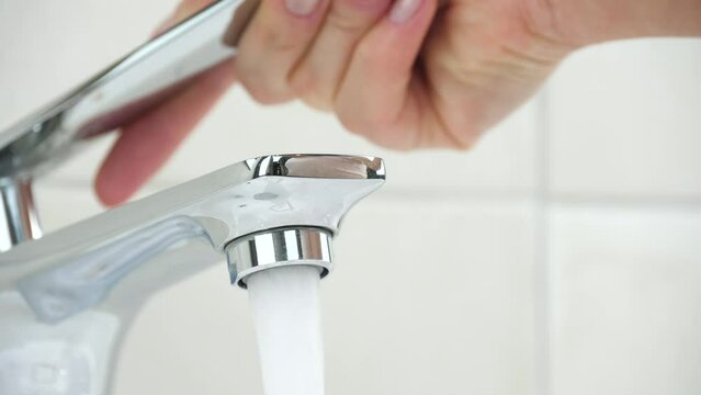 The hand opens the water tap in close-up. Fresh water reserves in nature. Water purification, iltration