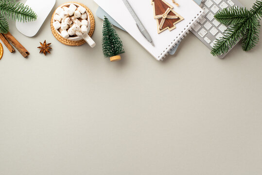 Christmas concept. Top view photo of workstation keyboard computer mouse reminders wood fir ornament cup of cocoa with marshmallow pine branches and cinnamon on isolated grey background with copyspace
