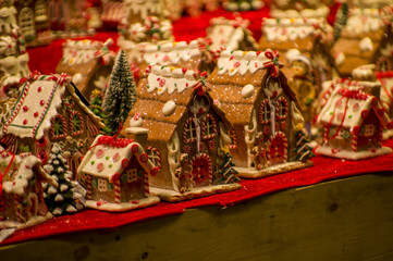 Fototapeta premium Advent Bazaar Stalls with glass, wooden, ceramic christmas souvenirs in a shop. Close up of festive decorations for tree in winter street night market during new year's holiday. Illuminated fair kiosk