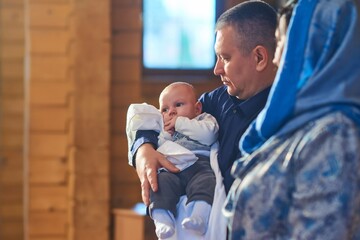 A small child at a baby christening ceremony in a church. the godfather holds a little boy in his...