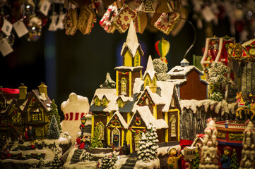 Advent Bazaar Stalls with glass, wooden, ceramic christmas souvenirs in a shop. Close up of festive decorations for tree in winter street night market during new year's holiday. Illuminated fair kiosk