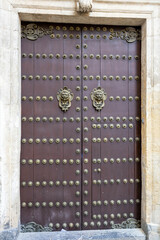 A wooden door with large brass rivets and artistic doorhandle in Cordoba, Andalusia, Spain
