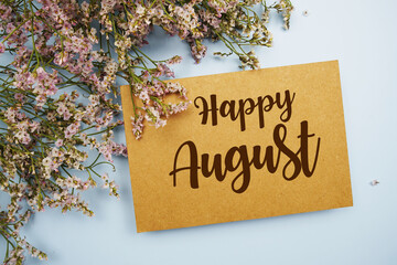 Happy August written on paper card with flower frame decoraton on pink background