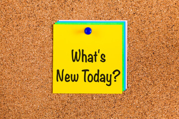 Yellow paper with words What's New Today? on a corkboard