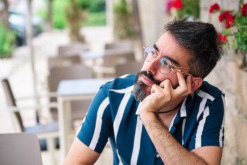 Close-up portrait of a businessman on the street. A handsome man with a beard and stylish clothes with thoughtful expression. Fashionable guy hipster.