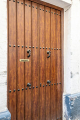 A wooden door with metal rivets and artistic doorhandles in Cordoba, Andalusia, Spain
