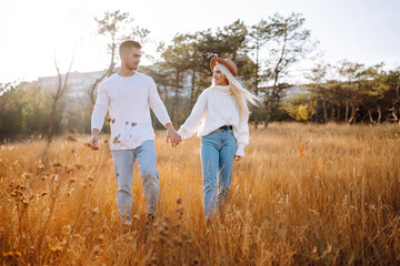 Naklejka na ściany i meble Loving Couple travel together, hike and walk in the autumn park in nature. People, lifestyle, relaxation and vacations concept.