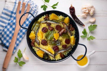 Migas with chorizo, sardines, bacon and green peppers cooked in a black paella. Typical Spanish tapa recipe.