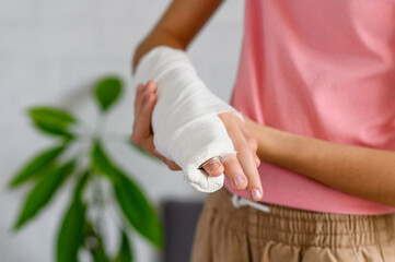 Teenage girl with a broken arm in the room. Close-up of a cast on the girl's hand. Selective focus...